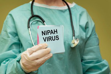 Sağlık Brifingi sırasında Yeşil Scrubs ve Stetoskop 'ta Nipah Virüs Alarm Kartı' nı elinde tutuyor.
