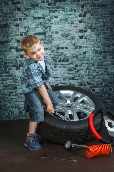 Boy is engaged in repair of wheels cars — Stock Photo, Image