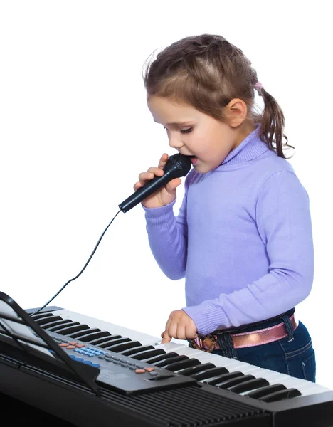 Portrait of a little girl sings and plays the piano — Stock Photo, Image