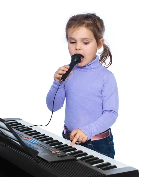 Porträtt av en liten flicka sjunger och spelar piano — Stockfoto