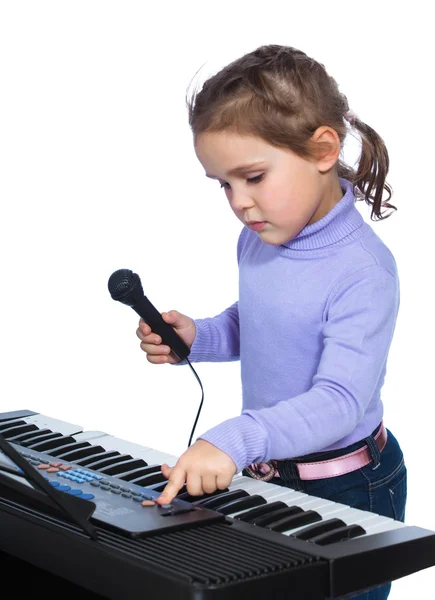 Portrait of a little girl sings and plays the piano — Stock Photo, Image