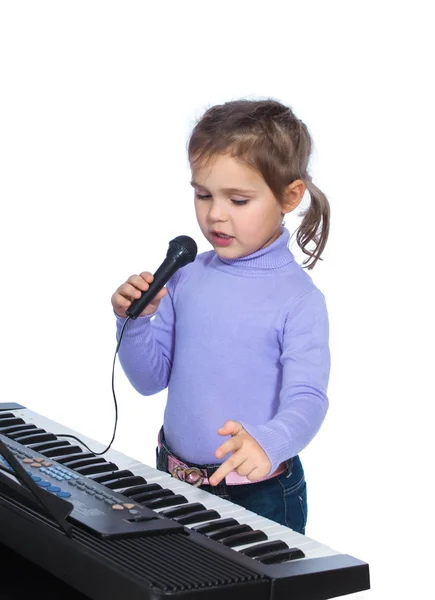 Портрет маленькой девочки поет и играет на пианино Стоковое Фото