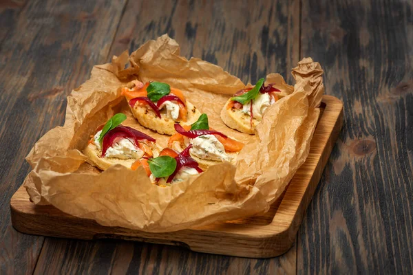 Toasts with red fish and greens on food paper on a wooden background — Stock Photo, Image