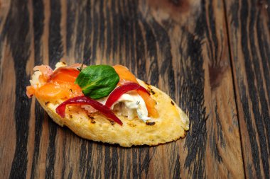 Kırmızı balıklı tostlar ve ahşap bir arka planda yeşiller.