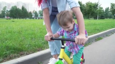 Anne oğluna ata binmeyi öğretiyor.