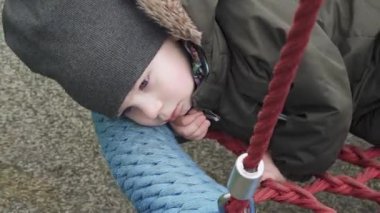 Çocuk yuvarlak bir salıncakta sallanıyor