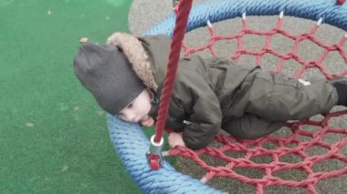 Çocuk yuvarlak bir salıncakta sallanıyor