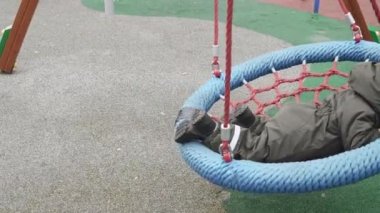 Çocuk yuvarlak bir salıncakta sallanıyor