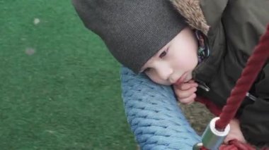 Çocuk yuvarlak bir salıncakta sallanıyor