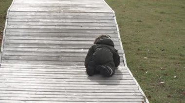 Şehir parkında ahşap atlama platformlarında koşan bir çocuk.