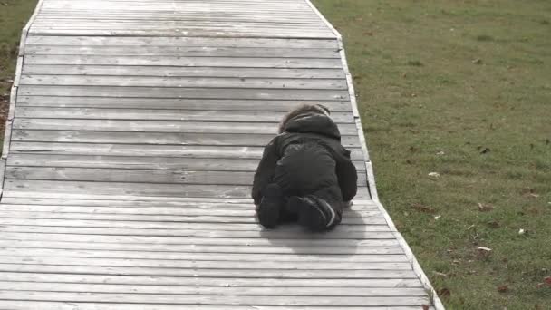 Хлопчик біжить на дерев'яних стрибках платформи в міському парку — стокове відео
