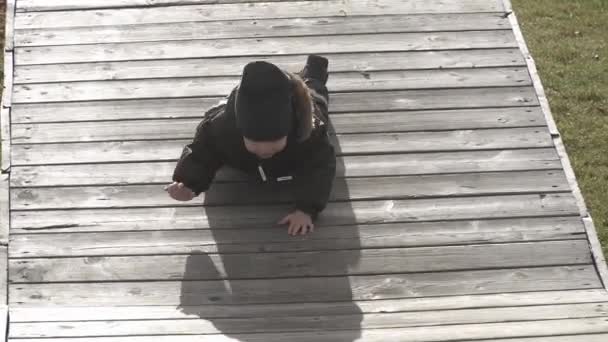 Junge läuft auf hölzernen Sprungbrettern im Stadtpark — Stockvideo