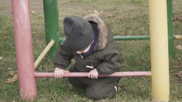 Jongen in overall op een oude speeltuin met roestige pijpen — Stockvideo