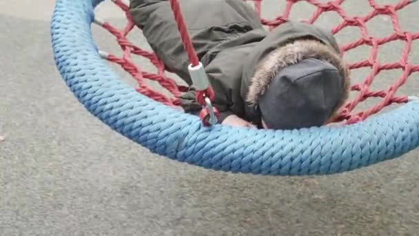 Chłopiec jeździ na okrągłym huśtawce siatki — Wideo stockowe