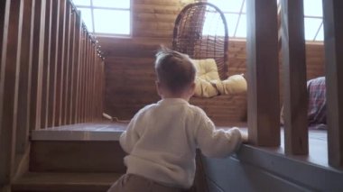 Oğlan tahta merdivenlere tırmanıyor.