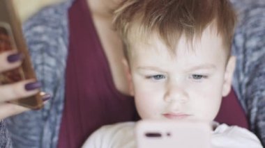 Çocuk annesinin kollarında oturuyor.