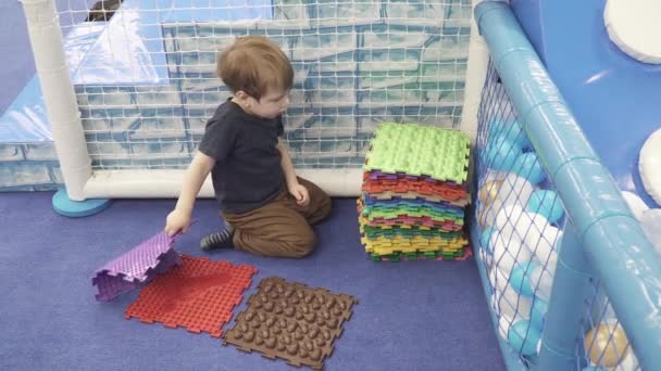 Niño pliega alfombras ortopédicas — Vídeo de stock