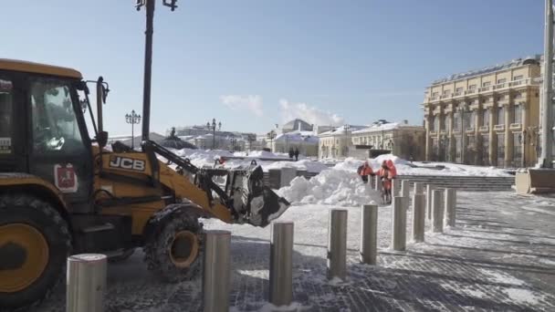 Yoğun bir kar yağışı sonrasında Manezhnaya Meydanı 'nda işçiler ve bir traktör kar temizliyor. — Stok video
