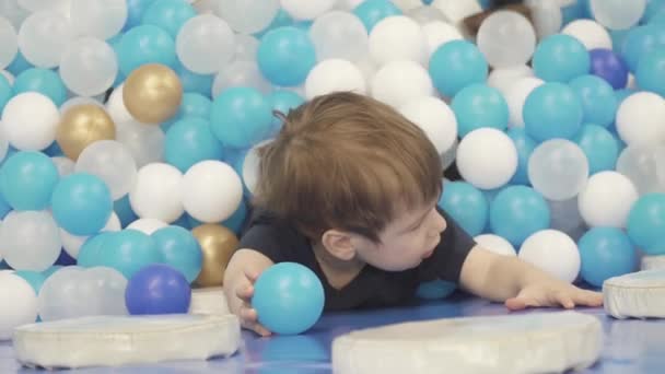 Ребенок в бассейне с шариками — стоковое видео