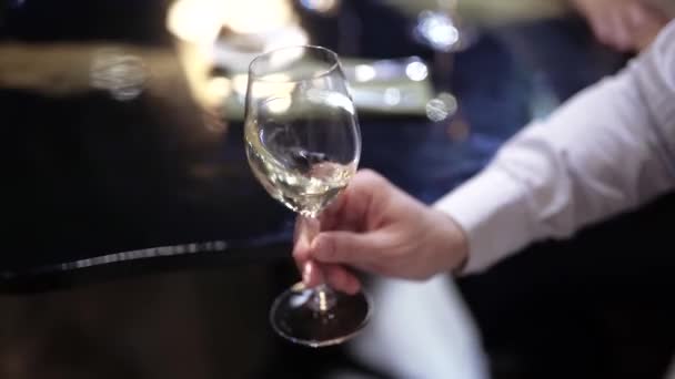 Egy fehér inges férfi tart egy pohár bort. — Stock videók