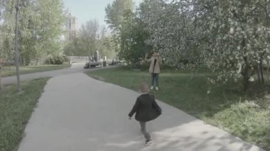 Parktaki sokakta arka planda fotoğraf çeken çocuk.