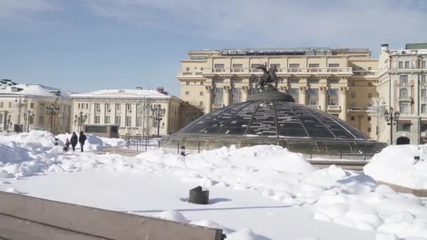 Snö-täckta kupoler i Okhotny Ryad köpcentrum och gågator rensas av snö med utsikt över Kreml från sidan av Alexander Garden — Stockvideo