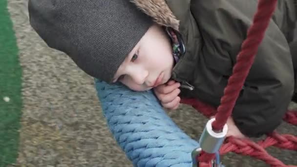 Chłopiec jeździ na okrągłym huśtawce siatki — Wideo stockowe