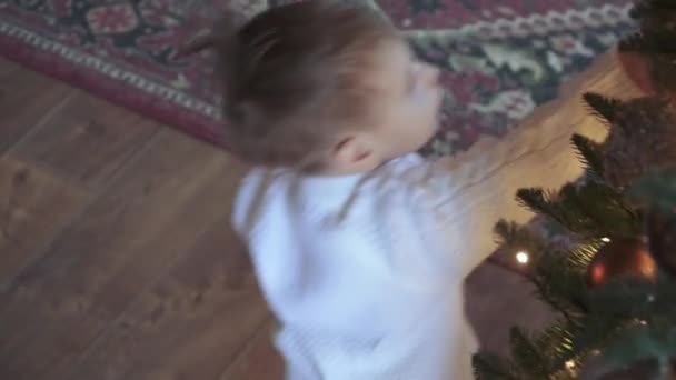 Kind jongen raakt en speelt met kerstboom — Stockvideo