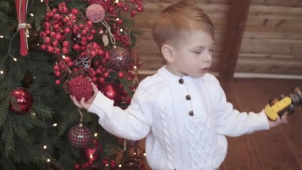 Menino toca e brinca com a árvore de Natal — Vídeo de Stock