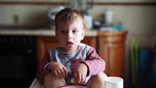 Jongen kijkt tekenfilms en eet koekjes — Stockvideo