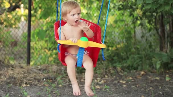 Niño en columpio en el jardín — Vídeos de Stock