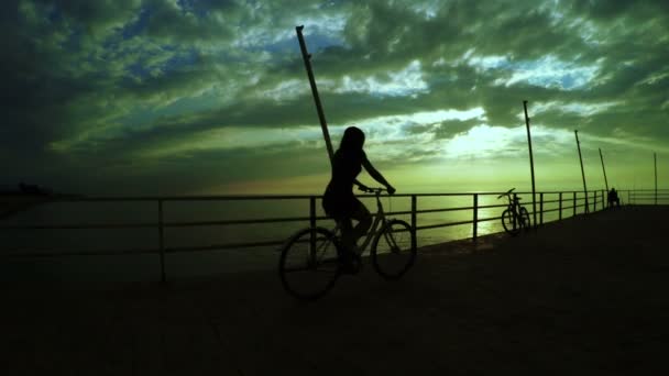 Meisje op de fiets op zonsondergang zee — Stockvideo