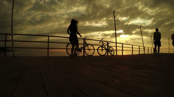 Fille sur les vélos au coucher du soleil mer — Video