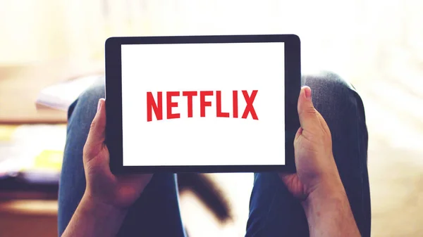 New York, ABD - 20 Şubat 2021: Tablet ekranda Netflix uygulama logosu, evde çevrimiçi videolar izlerken kişinin elinde mobil bir cihaz tutmasına odaklı.