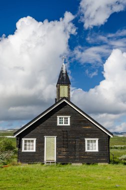 Yeşil tepelerdeki küçük siyah ahşap kilise. Tundra Çekiç Festivali.