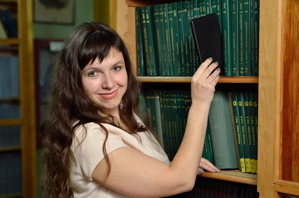 Una donna con un gadget in biblioteca — Foto Stock