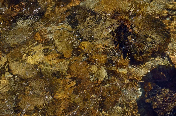 Close-up do leito do rio através de água limpa que flui — Fotografia de Stock