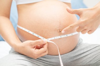 Hamile kadın karnını ölçüyor ve senin parmağını hamileliğinde kullanıyor.