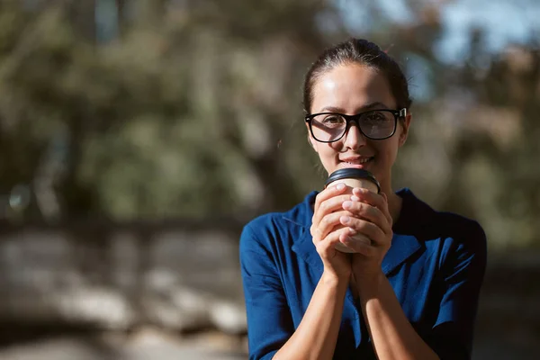 Una bella donna che si riscalda con una tazza di caffe '. Signora in bicchieri nel parco. Prendere pausa e concetto di tempo libero, copiare lo spazio — Foto Stock