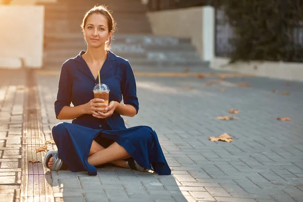 Mulher atraente em vestido azul sentado no chão. Tempo livre na natureza. Faça uma pausa e café conceito de tempo, espaço de cópia — Fotografia de Stock