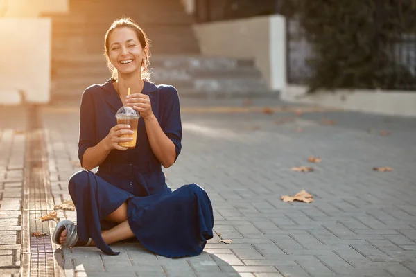 Wanita lucu tertawa minum minuman sambil duduk di tanah. Tempat baru, gaya jalan dan konsep emosi baru, menyalin ruang — Stok Foto