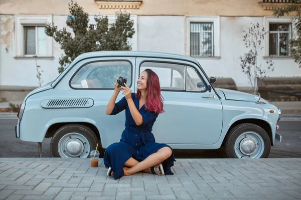 Wanita tersenyum mengambil gambar di kamera foto. Old mobil biru kuno. Waktu untuk bepergian, emosi baru dan konsep tempat baru — Stok Foto