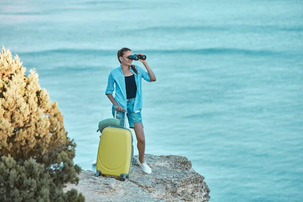 Woman looking in binoculars. Panoramic view from cliff. Summer vacation freedom and travel time concept, copy space — Stock Photo, Image