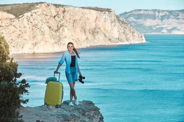 Temps de détente et concept de vacances d'été, espace de copie. Joyeux jeune femme avec des bagages posant sur fond de paysage. — Photo