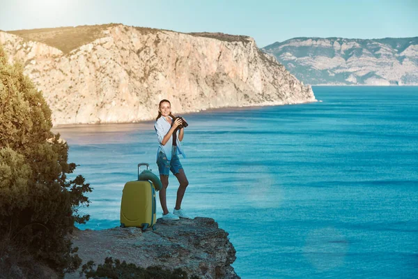 Χαρούμενη χαμογελαστή κυρία που στέκεται στη θάλασσα. Κίτρινες αποσκευές για ταξίδι. Νέα έννοια εδάφους και επαγγελματικών ταξιδιών, αντίγραφο χώρου — Φωτογραφία Αρχείου