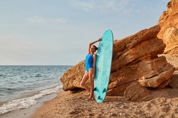 Весела леді спирається на дошку для серфінгу на фоні природи. Час пригод, пляжна релаксація та концепція літніх канікул — стокове фото