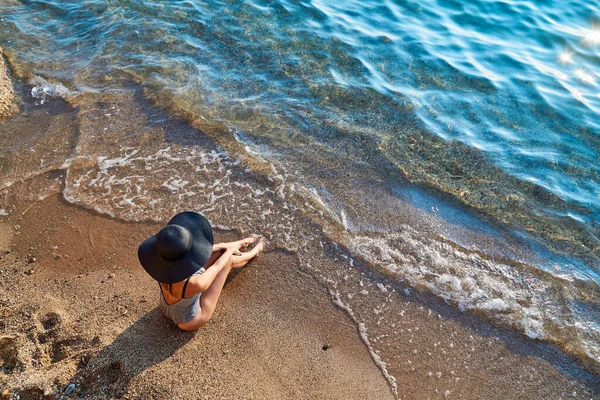 Vue du dessus de jolie femme en maillot de bain posant sur le bord de mer. Plage, vagues de mer et mousse. Ambiances estivales et concept d'été Photo De Stock