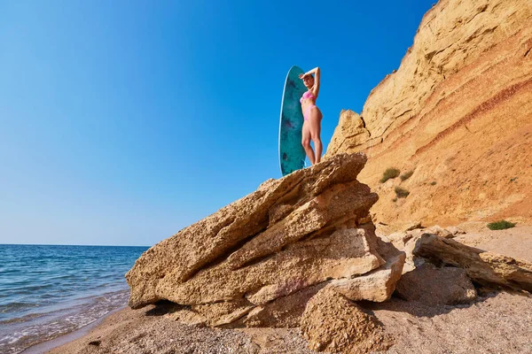 Jolie dame sur le rocher avec planche de surf. Côtier et vue sur l'océan. Sports de surf, temps d'aventure, idée de jour de plage, espace de copie Images De Stock Libres De Droits