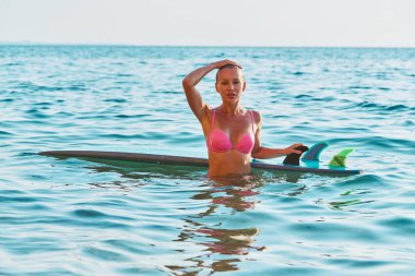 Denize daldıktan sonra çekici bir kadın. Sörf tahtası suda yüzüyor. Sörf sporu, yaz tatili ve tatil gezisi konsepti