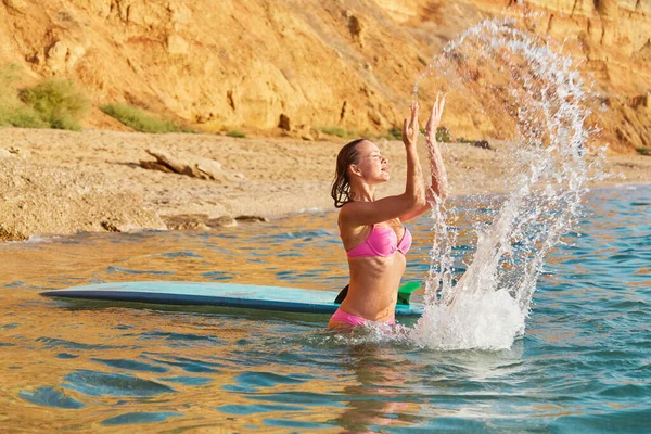 Идея летнего времени, серфинг-спорт, желание приключений, копировальное пространство. Красивая девушка в морской воде в купальнике и доске для серфинга Стоковая Картинка